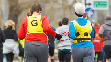 Eine taubblinde Person joggt neben Ihrer Assistentin